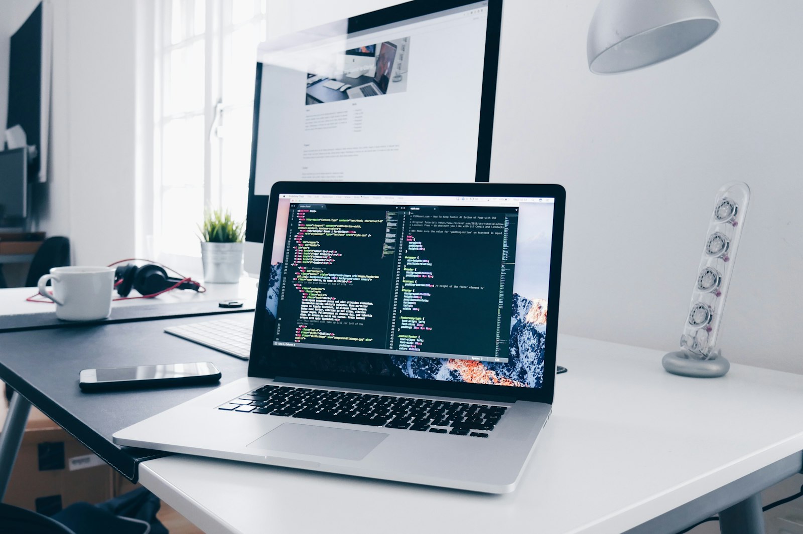 Et ryddig arbeidsbord med laptop som viser en nettside, kaffekopp og notatbok